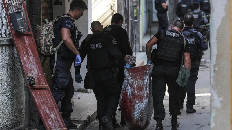 Foto de policiais carregando um corpo na favela